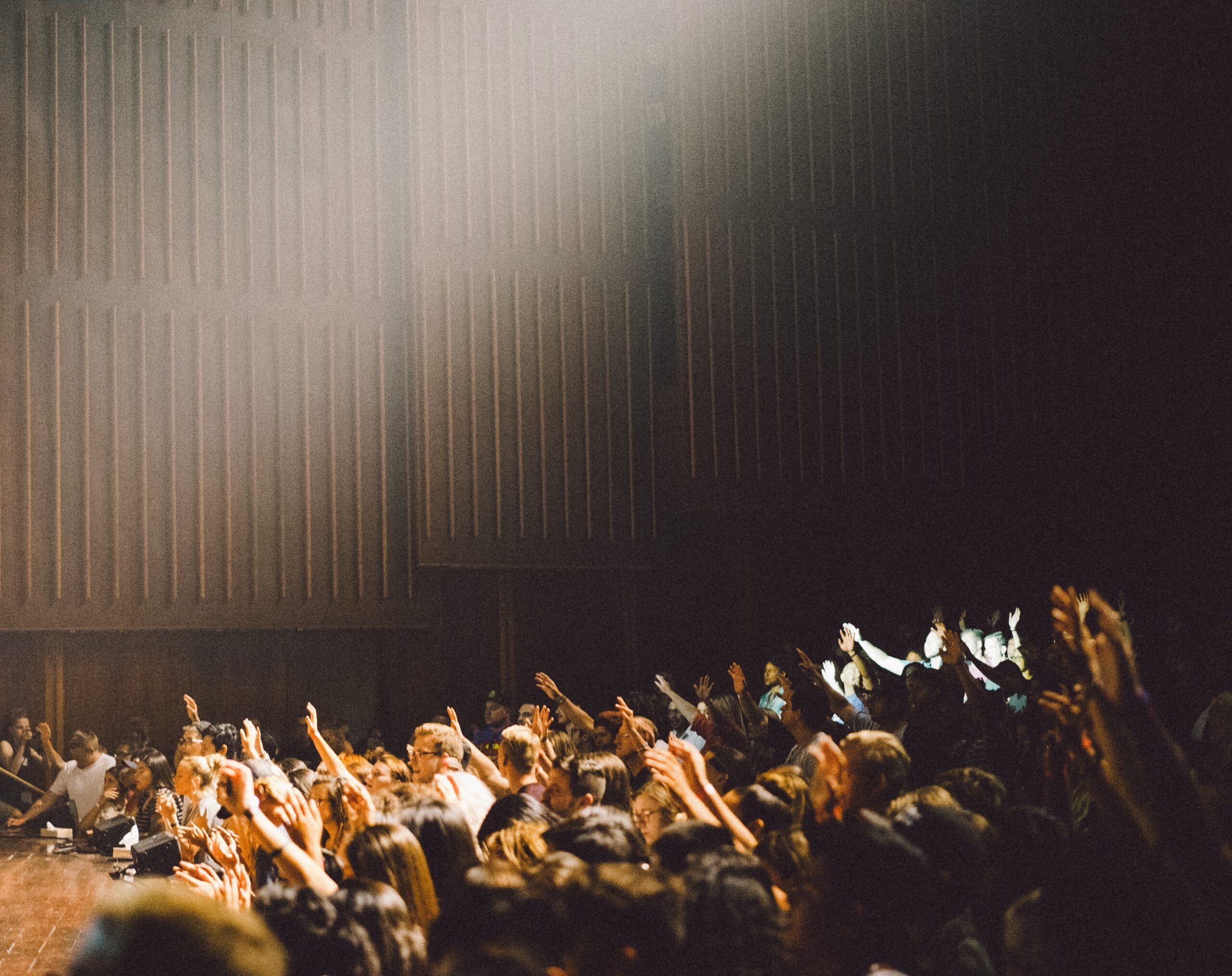 People raising their hands in a hall